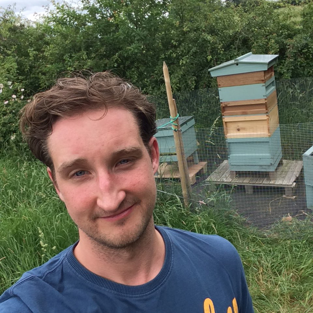 A photo of me, in front of my hive, looking slightly dishevelled having just stolen a load of honey